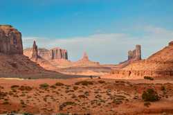 Landscape photography of rock formation in a desert with a cloudy blue sky in the background.
