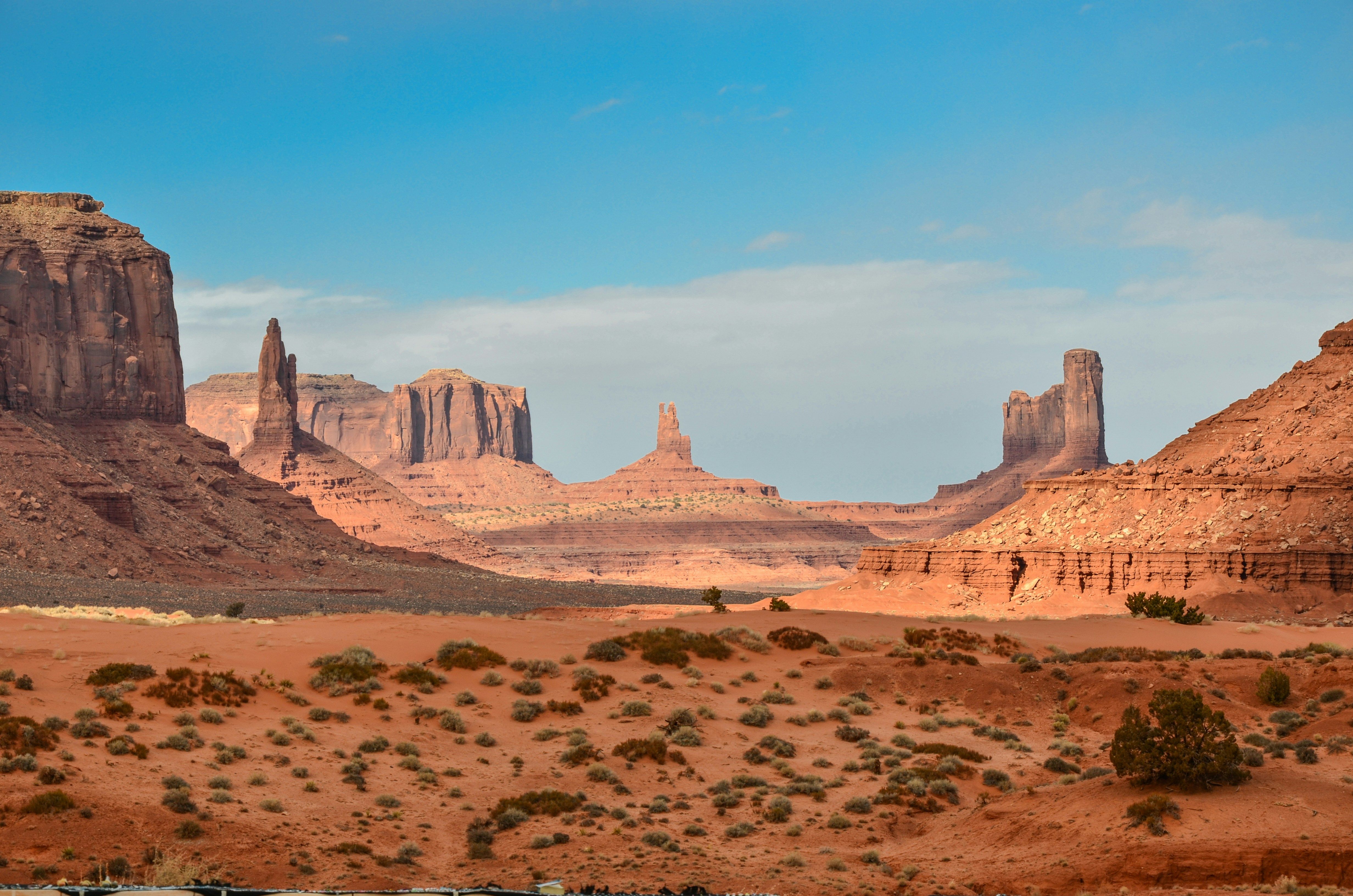 Landscape photography of rock formation in a desert with a cloudy blue sky in the background.