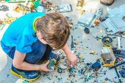 Child taking apart old electronics, with circuit boards and parts spread on the ground