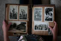 A person looking at an old photo albbum with black and white polaroid pictures.