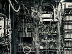 A server room with lots of cables running into hardware. It looks very messy.