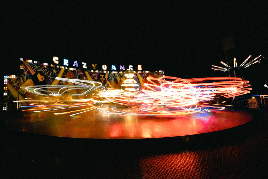 A theme park ride at night. The lights of the ride are blurred due to the long exposure.